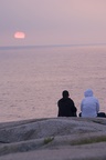 A couple watching sunset in Peggy's cove.